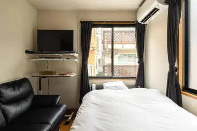 a bedroom with a bed and a couch and a window at \u30a2\u30f3\u30c9\u30b9\u30c6\u30a4\u897f\u65b0\u4e95 in Tokyo