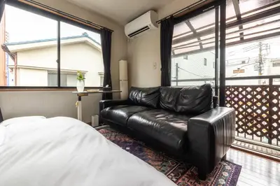 a living room with a leather couch and a window at \u30a2\u30f3\u30c9\u30b9\u30c6\u30a4\u897f\u65b0\u4e95 in Tokyo
