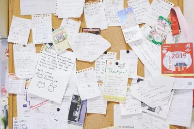 a wall filled with lots of papers and notes at Rize Apartments in Tokyo