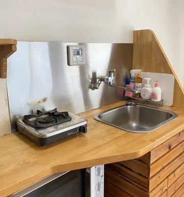 a kitchen counter with a stove and a sink at Rize Apartments in Tokyo