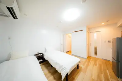 two beds in a room with wooden floors at Tokyo Skytree\u96fb\u8eca3\u5206 \u79cb\u8449\u539f\u307e\u30677\u5206 \u6d45\u8349\u6a4b\u307e\u30674\u5206 \u6d17\u9762\u53f0\u30b7\u30e3\u30ef\u30fc\u5ba4\u304c\u5225 \u30ad\u30c3\u30c1\u30f3\u5b8c\u5099 \u9326\u7cf8\u753a\u99c5 \u89b3\u5149\u5730\u30a2\u30af\u30bb\u30b9\u826f\u597d 303\u90e8\u5c4b in Tokyo