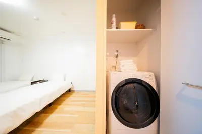 a washer and dryer in a room with a bed at Tokyo Skytree\u96fb\u8eca3\u5206 \u79cb\u8449\u539f\u307e\u30677\u5206 \u6d45\u8349\u6a4b\u307e\u30674\u5206 \u6d17\u9762\u53f0\u30b7\u30e3\u30ef\u30fc\u5ba4\u304c\u5225 \u30ad\u30c3\u30c1\u30f3\u5b8c\u5099 \u9326\u7cf8\u753a\u99c5 \u89b3\u5149\u5730\u30a2\u30af\u30bb\u30b9\u826f\u597d 303\u90e8\u5c4b in Tokyo