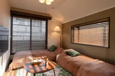 a bedroom with two beds and a table and a window at LiveGRACE Hotel Shibuya \u6e0b\u8c37\u897f\u65b0\u5bbf in Tokyo