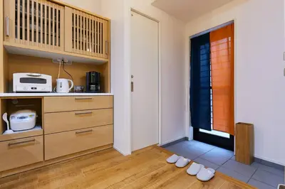a kitchen with wooden cabinets and shoes on the floor at EK House SkyTree in Tokyo