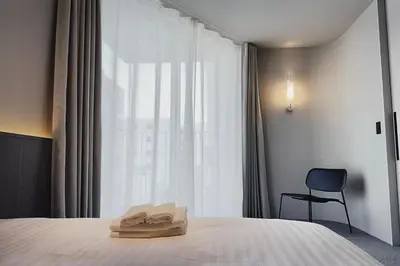 a bedroom with a bed and a chair and a window at Hotel Rakuragu in Tokyo