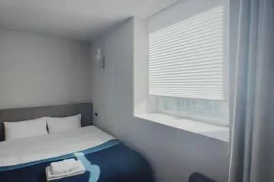 a small bedroom with a bed and a window at Hotel Rakuragu in Tokyo