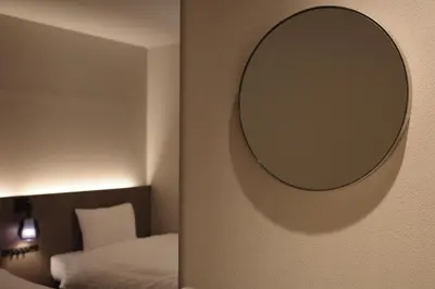 a mirror on a wall next to a bed at Hotel Rakuragu in Tokyo