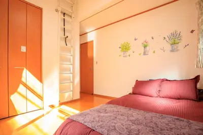 a bedroom with a bed with red sheets and flowers on the wall at Sky House BnB in Tokyo