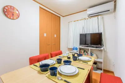 a dining room with a table with chairs and a television at Sky House BnB in Tokyo
