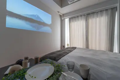 a bedroom with a table with plates and a large screen at Tokyo's best spot Shibuya! 3person room Free Wi-Fi in Tokyo