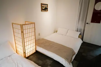 a small room with two beds and a door at Eden House in Tokyo