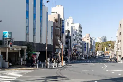 a city street with people standing on the side of the road at KISETSU\u65e9\u7a32\u7530l in Tokyo