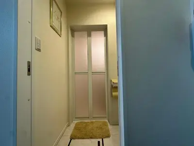 a hallway with a door to a bathroom with a rug at \u30a2\u30a4\u30ea\u30b9\u30b3\u30fc\u30c8 in Tokyo