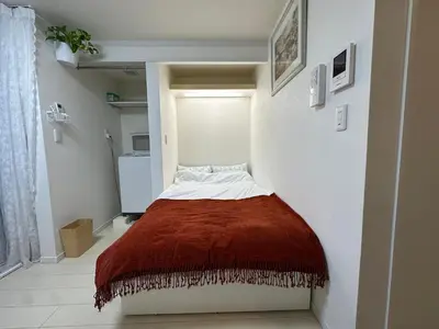 a small bedroom with a bed with a brown blanket at \u30a2\u30a4\u30ea\u30b9\u30b3\u30fc\u30c8 in Tokyo