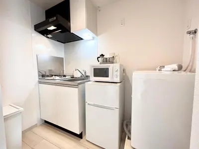 a small kitchen with a microwave and a refrigerator at TYO Ikebukuro Designer’s Apt 101 in Tokyo