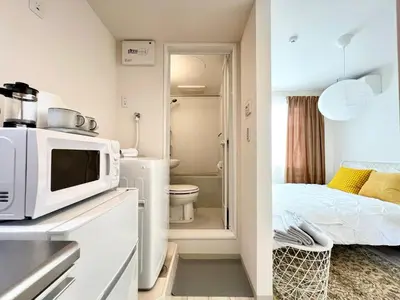 a small kitchen with a microwave and a bedroom at TYO Ikebukuro Designer’s Apt 101 in Tokyo