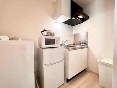 a small kitchen with a microwave and a refrigerator at TYO Ikebukuro Designer’s Apt 102 in Tokyo
