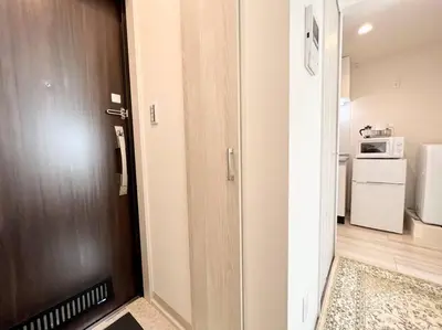 a room with a door and a kitchen with a microwave at TYO Ikebukuro Designer’s Apt 201 in Tokyo
