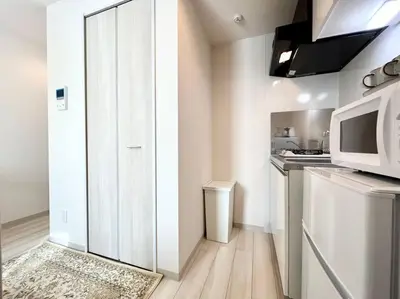 a kitchen with a white door and a microwave at TYO Ikebukuro Designer’s Apt 301 in Tokyo