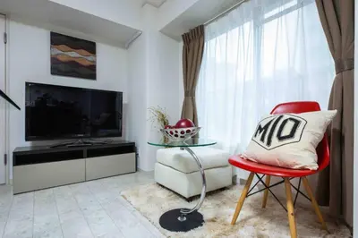 a living room with a red chair and a television at Asakusa 2 Bedroom Apartment \u897f\u6d45\u83492LDK\u5e83\u3005\u30d5\u30a1\u30df\u30ea\u30fcor\u30b0\u30eb\u30fc\u30d7 in Tokyo