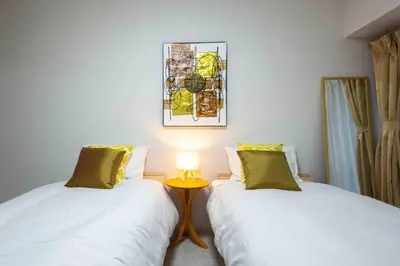 two beds in a room with a table with a lamp at Asakusa 2 Bedroom Apartment \u897f\u6d45\u83492LDK\u5e83\u3005\u30d5\u30a1\u30df\u30ea\u30fcor\u30b0\u30eb\u30fc\u30d7 in Tokyo
