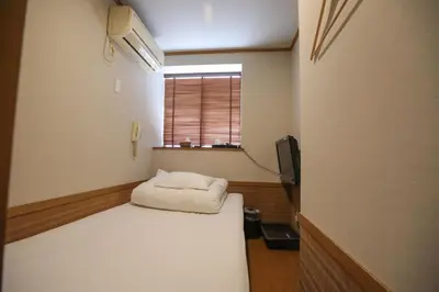 a small room with a bed and a window at \u30d7\u30c1\u30db\u30c6\u30eb\u3000\u30b3\u30b9\u30e2\u30b9 in Tokyo