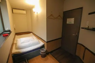 a small room with a bed and a door at \u30d7\u30c1\u30db\u30c6\u30eb\u3000\u30b3\u30b9\u30e2\u30b9 in Tokyo