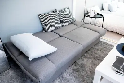 a gray couch with a pillow in a living room at #8 3mins to station 1stop to Shinjuku Central Shinjuku apartment with plenty of Sunlight in Tokyo