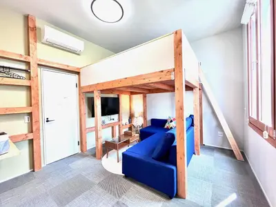 a living room with a loft bed and a blue couch at \u6c60\u888bApila in Tokyo