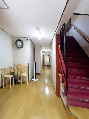 a hallway with stairs and a clock on the wall at HOTEL HOUSE LEE in Tokyo