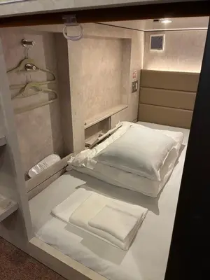 a small room with a bed with white sheets at Book Tea Bed SHIBUYA in Tokyo