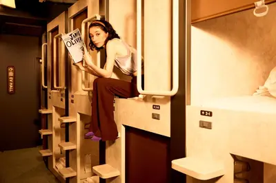 a woman sitting on the ledge of a train holding a sign at Book Tea Bed SHIBUYA in Tokyo