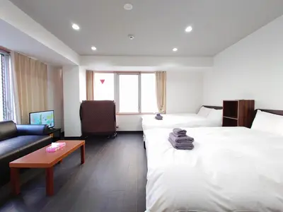 a hotel room with two beds and a couch at peter hotel akihabara in Tokyo