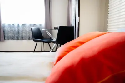 a bed with orange pillows and chairs in a room at PREMIER suite Shinjuku Akebonobashi front in Tokyo