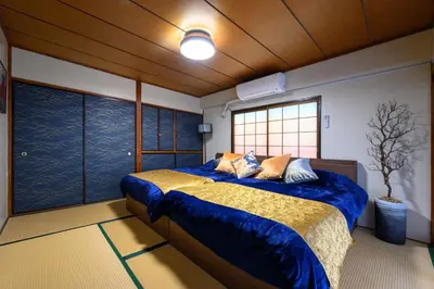 a bedroom with a bed with blue sheets and a window at PREMIER suite Shinjuku Akebonobashi front in Tokyo