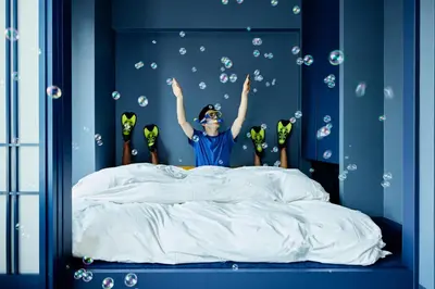 a boy jumping in bed with his arms in the air at Section L Tsukiji in Tokyo