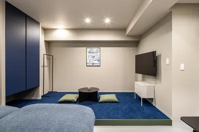 a room with a tv and a blue carpet at Section L Kuramae - Asakusa in Tokyo