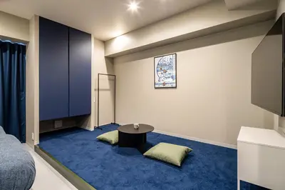 a room with a bed and a table on a blue carpet at Section L Kuramae - Asakusa in Tokyo