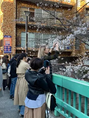 a woman taking a picture of a crowd of people at COCO Nakameguro 202 in Tokyo