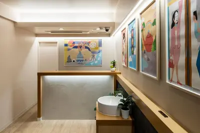 a bathroom with a sink and paintings on the wall at Section L Hamamatsucho in Tokyo