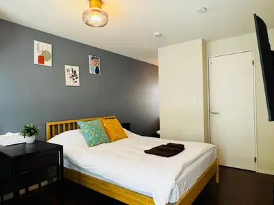 a bedroom with a bed with white sheets and a table at Lucky you! YOTSUYA in Tokyo