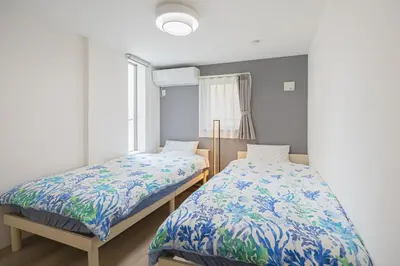 a bedroom with two beds and a window at \u6e0b\u8c37 \u5e83\u308150m2 2LDK \u4ee3\u3005\u6728\u516c\u5712\u99c5\u5f92\u6b695\u5206 \u5bb6\u65cf\u306b\u304a\u3059\u3059\u3081 in Tokyo