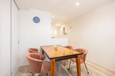 a dining room with a wooden table and pink chairs at \u6e0b\u8c37 \u5e83\u308150m2 2LDK \u4ee3\u3005\u6728\u516c\u5712\u99c5\u5f92\u6b695\u5206 \u5bb6\u65cf\u306b\u304a\u3059\u3059\u3081 in Tokyo