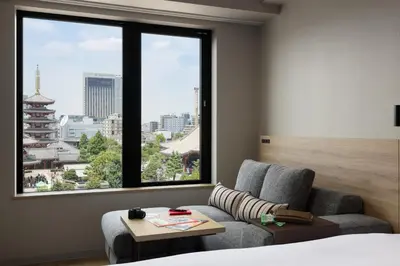 a room with a bed and a couch and a window at OMO3 Asakusa by Hoshino Resorts in Tokyo