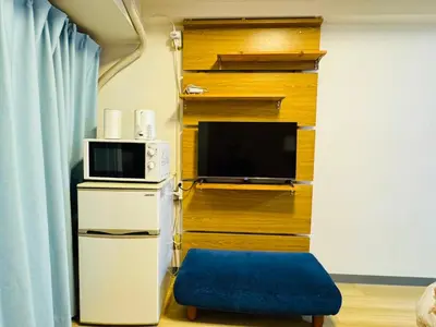 a living room with a tv and a blue ottoman at Kabukicho-503-SJ0010 in Tokyo