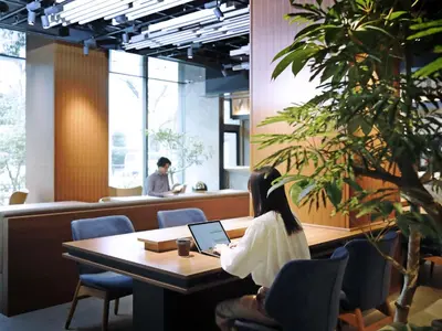 a woman sitting at a table with a laptop at &Here TOKYO UENO in Tokyo