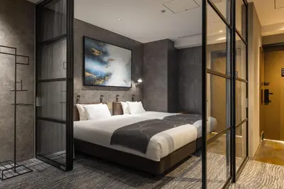 a bedroom with a bed and a painting on the wall at &Here TOKYO UENO in Tokyo