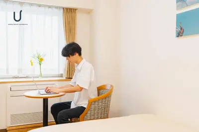 a man sitting at a table using a laptop at Forest Hongo by unito in Tokyo