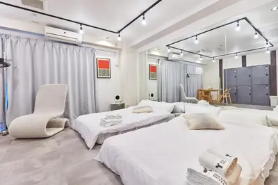 a white room with two beds and a chair at Tora Hotel Asakusa in Tokyo