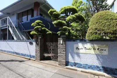 a blue house with a fence with a sign on it at Oyado Tsuki to Kawa in Tokyo